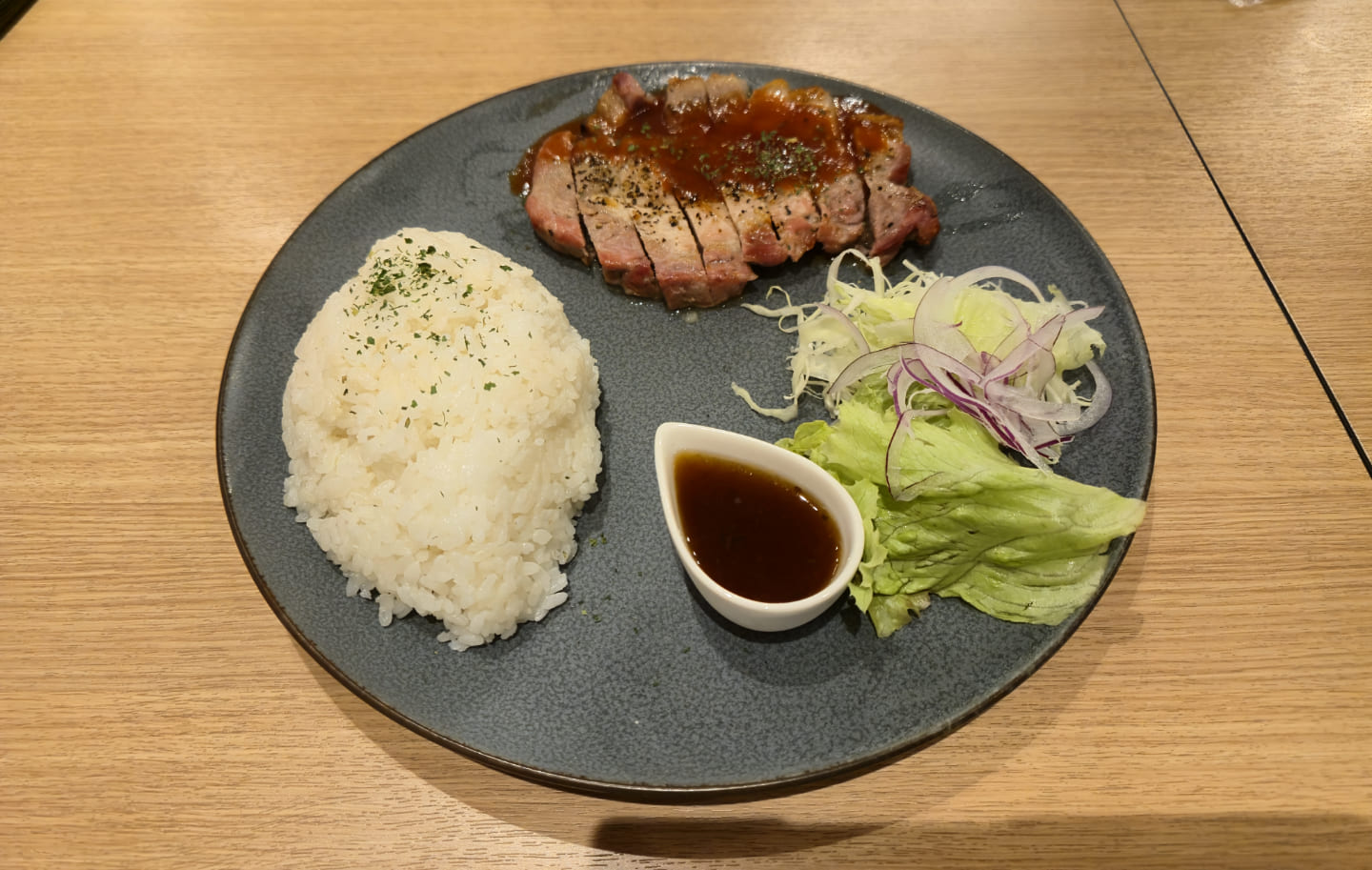 プレートに白いご飯とアグー豚のステーキとサラダが乗っている